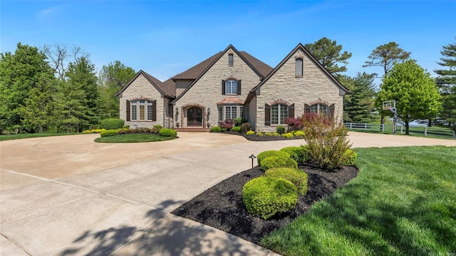 view of front of home featuring curved driveway, a front lawn, and stone siding