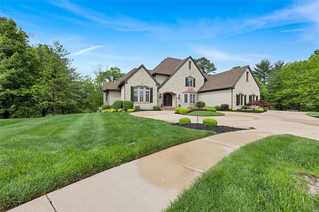 french country inspired facade with a front yard and stone siding