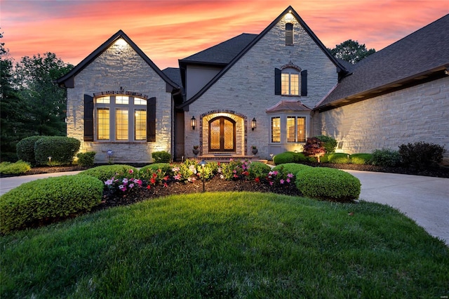french country inspired facade with stone siding and a front lawn