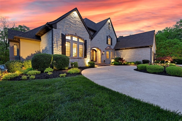 french provincial home featuring a shingled roof, a front yard, and stone siding