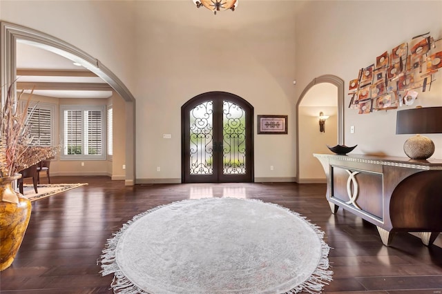 entrance foyer with french doors, arched walkways, and dark wood-style floors