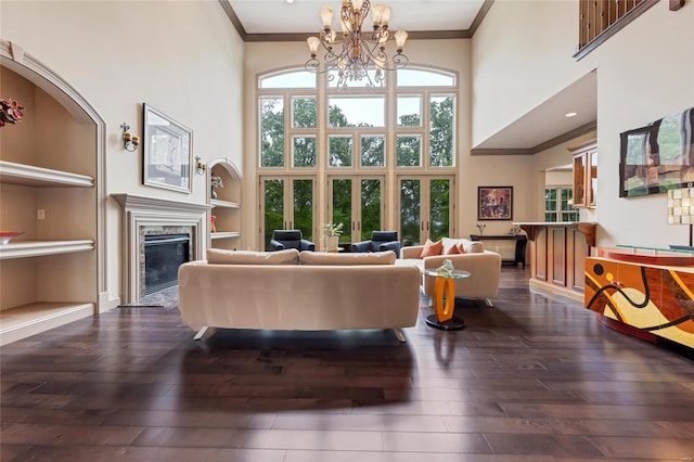 living area with crown molding, a notable chandelier, dark wood-style floors, and a towering ceiling