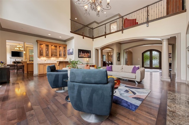 living area with arched walkways, a high ceiling, ornate columns, and dark wood-type flooring