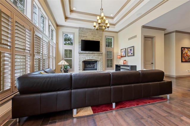 living room with visible vents, crown molding, a raised ceiling, a notable chandelier, and hardwood / wood-style floors