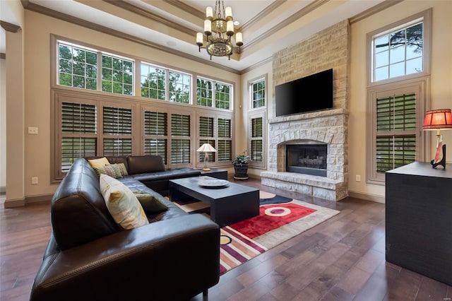 living room with ornamental molding, wood finished floors, baseboards, a raised ceiling, and a chandelier