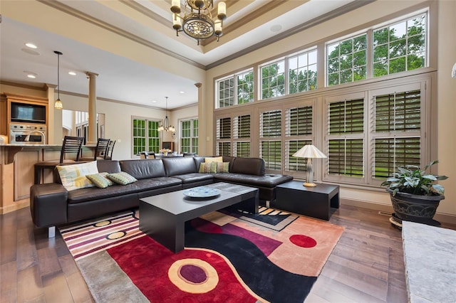 living area featuring a raised ceiling, ornamental molding, wood-type flooring, and a chandelier