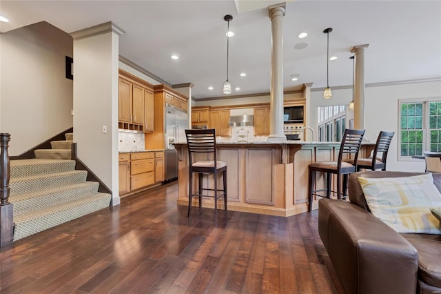 kitchen with crown molding, built in appliances, dark wood-style floors, and wall chimney range hood