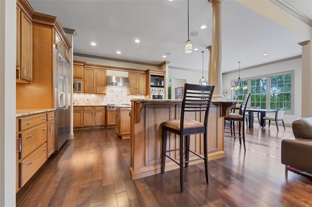 kitchen featuring brown cabinets, ornamental molding, and wall chimney exhaust hood