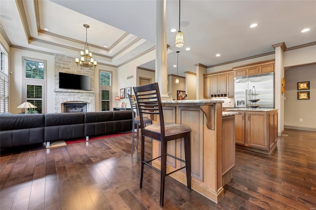 kitchen featuring ornamental molding, built in fridge, open floor plan, and a kitchen bar