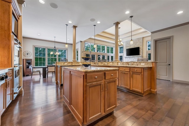 kitchen featuring brown cabinets, a large island, a wealth of natural light, and a fireplace