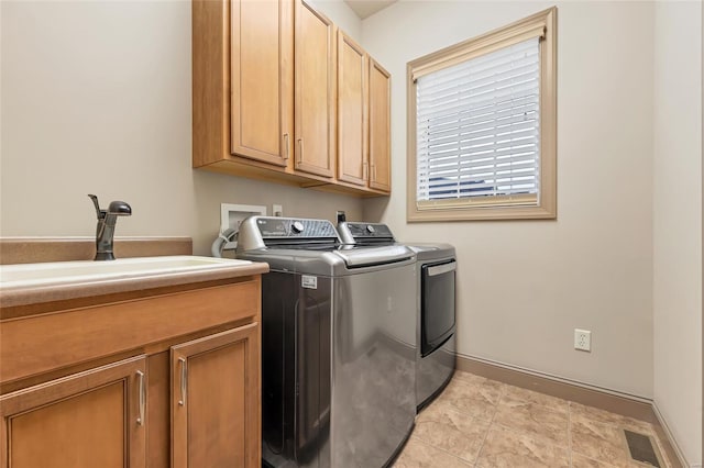 washroom featuring cabinet space, a sink, baseboards, visible vents, and washing machine and dryer