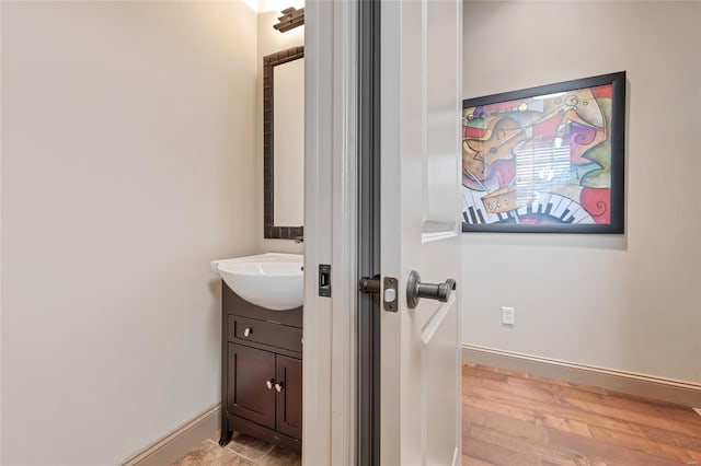 bathroom featuring vanity, baseboards, and wood finished floors