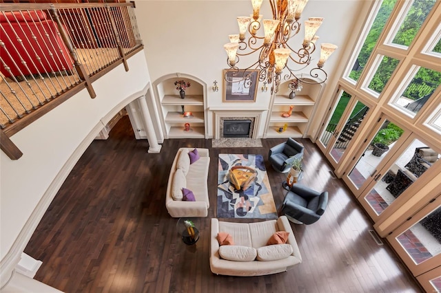 living area featuring arched walkways, wood-type flooring, and a towering ceiling
