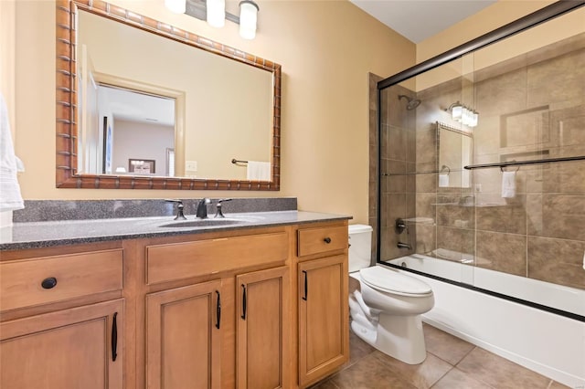 full bathroom featuring vanity, shower / bath combination with glass door, tile patterned flooring, and toilet
