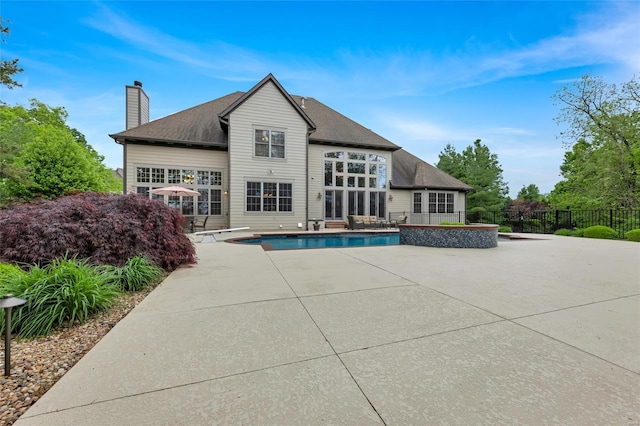 rear view of house with a chimney, a fenced in pool, fence, a patio, and a shingled roof