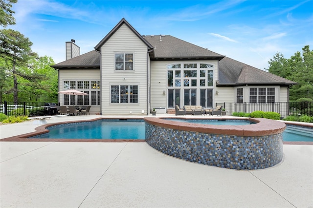 view of swimming pool with a pool with connected hot tub, fence, and a patio area