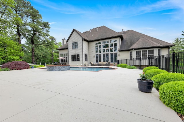 rear view of house featuring a shingled roof, a fenced in pool, a fenced backyard, a chimney, and a patio area