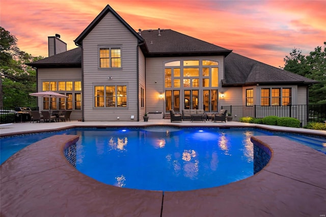 pool at dusk featuring a fenced in pool, fence, a patio area, and outdoor lounge area