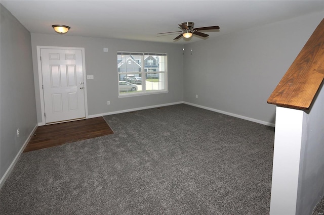 foyer entrance with dark colored carpet, a ceiling fan, and baseboards