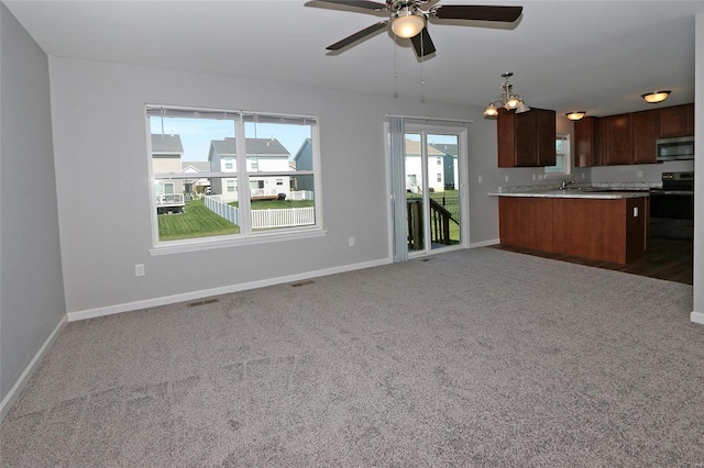 unfurnished living room featuring visible vents, baseboards, carpet, and ceiling fan