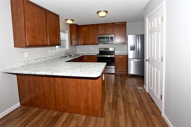 kitchen featuring a peninsula, light countertops, appliances with stainless steel finishes, and dark wood-style flooring