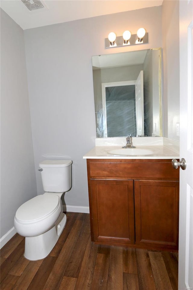 bathroom with toilet, visible vents, baseboards, wood finished floors, and vanity