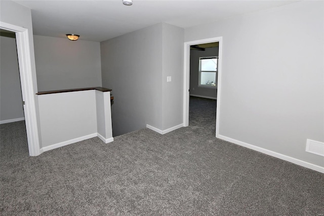 empty room with baseboards, dark colored carpet, and visible vents