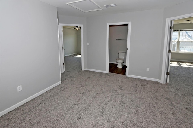 unfurnished bedroom with attic access, a spacious closet, carpet, baseboards, and visible vents