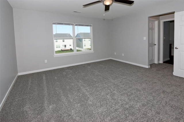 empty room with dark carpet, ceiling fan, baseboards, and visible vents