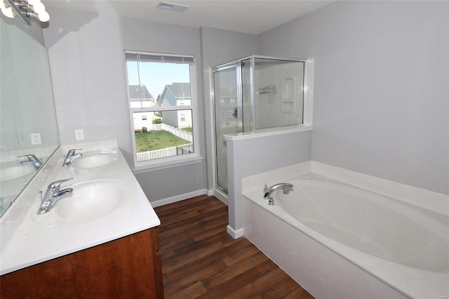 bathroom with wood finished floors, visible vents, a stall shower, and a sink