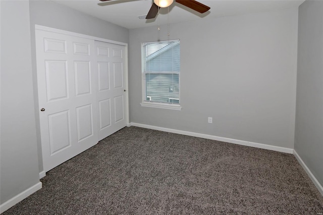 unfurnished bedroom featuring baseboards, dark carpet, a closet, and ceiling fan