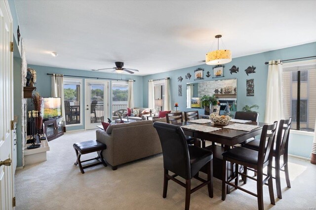 dining area with a ceiling fan, a glass covered fireplace, and light carpet