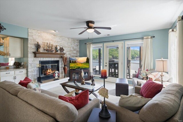 living area with a stone fireplace, a ceiling fan, carpet, and visible vents