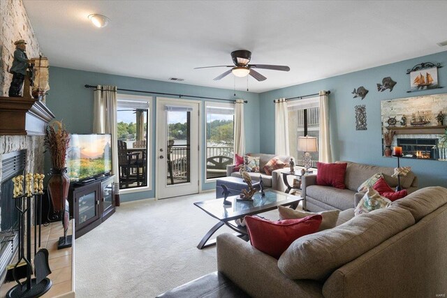 living room with a glass covered fireplace, light carpet, a ceiling fan, and visible vents