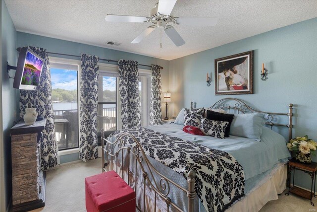 bedroom featuring carpet floors, a textured ceiling, visible vents, and ceiling fan