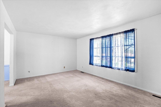 unfurnished room with baseboards, carpet flooring, and visible vents