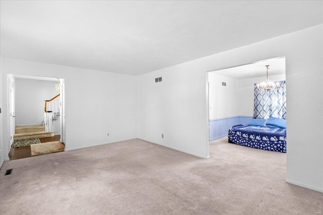 unfurnished living room with visible vents, carpet flooring, stairs, and an inviting chandelier