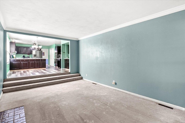unfurnished living room featuring baseboards, ornamental molding, visible vents, and an inviting chandelier