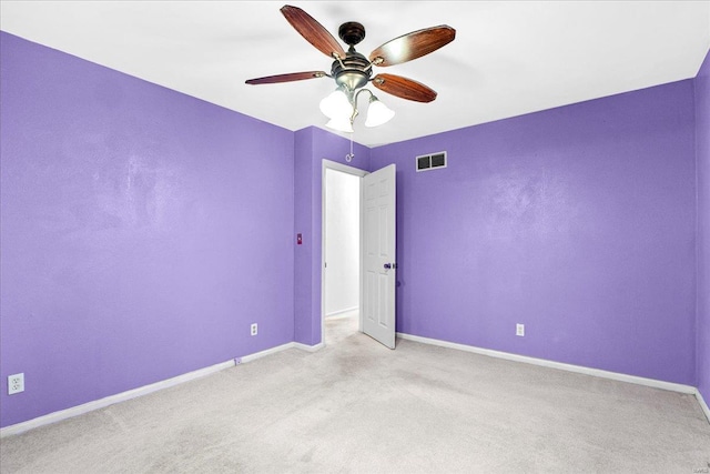 carpeted empty room with baseboards, a ceiling fan, and visible vents