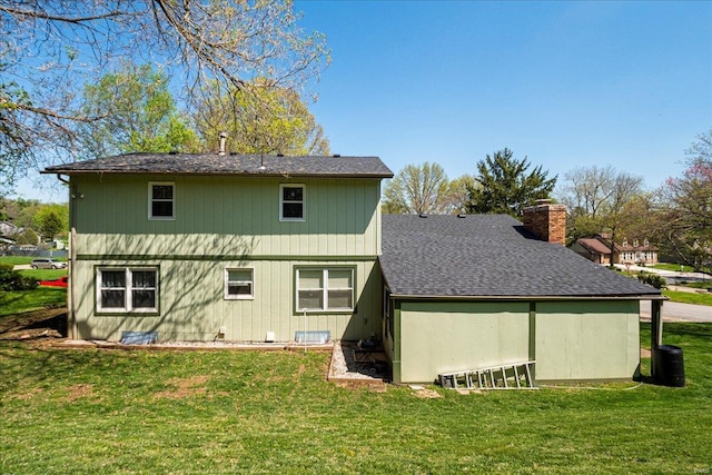 rear view of property with a lawn, a shingled roof, and a chimney