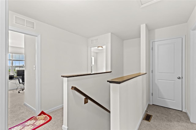 corridor featuring light colored carpet, baseboards, an upstairs landing, and visible vents