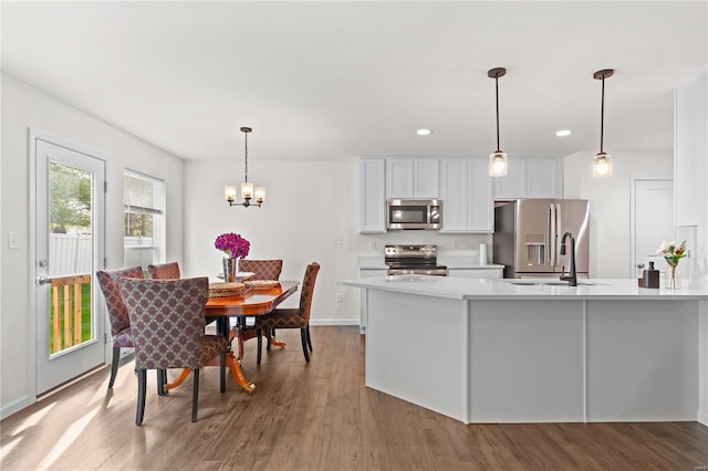 kitchen with a notable chandelier, light countertops, stainless steel appliances, white cabinetry, and wood finished floors