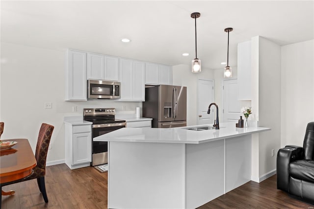 kitchen with stainless steel appliances, dark wood finished floors, a sink, and a peninsula