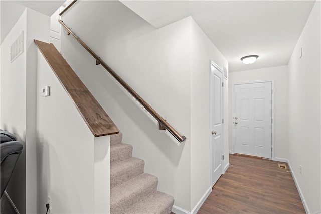 stairs featuring baseboards, wood finished floors, and visible vents