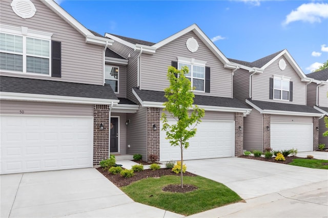 townhome / multi-family property with concrete driveway, brick siding, and a garage