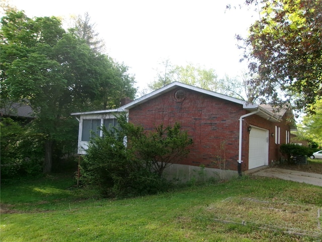 view of side of property featuring brick siding, an attached garage, concrete driveway, and a lawn