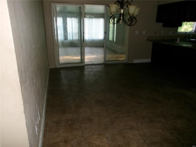 unfurnished dining area featuring an inviting chandelier, a sink, and dark tile patterned flooring