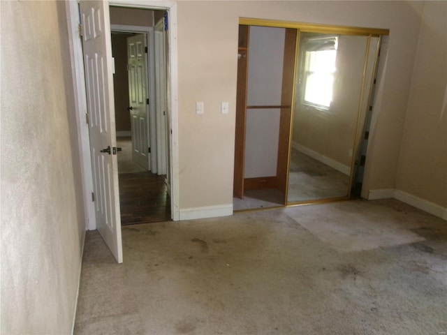 unfurnished bedroom featuring baseboards, carpet flooring, and a closet