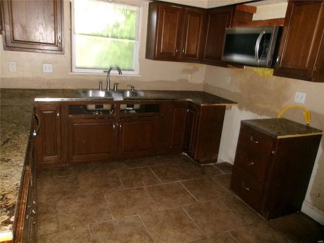 kitchen with stainless steel microwave, a sink, and stone counters