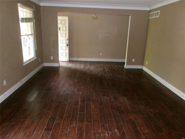 empty room with a wealth of natural light, dark wood-style flooring, and visible vents